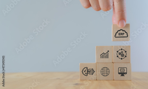 Cloud ERP service concept. Enterprise resources planning business and technology concept. Hand puts ERP business management software as cloud computing service with working on cloud icon on wood cubes