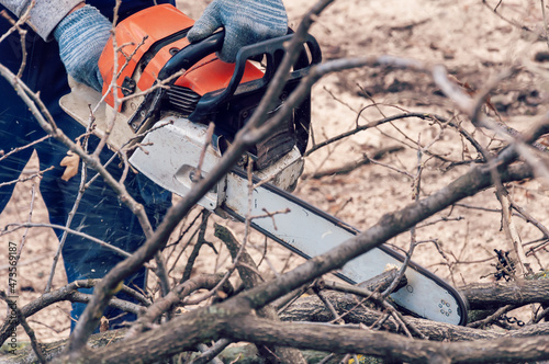 Hands Of Worker Cutting The Log By Chainsaw Machine With Sawdust Splash Around