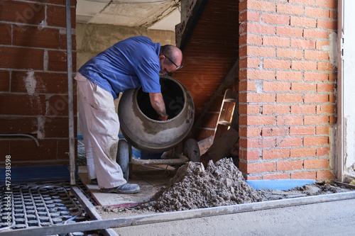 Construction worker taking out the concrete from the concrete the mixer.