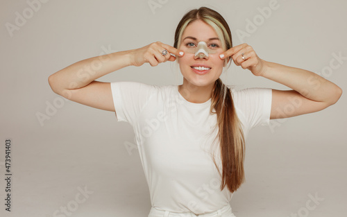 A young woman with a bandage on her nose after rhinoplasty rejoices