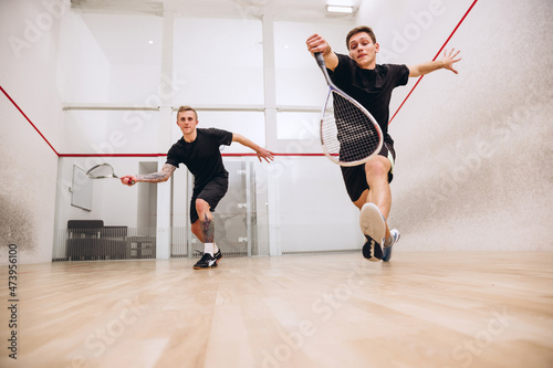 Full-length portrait of two young playful boys training together, playing squash isolated over sport studio background