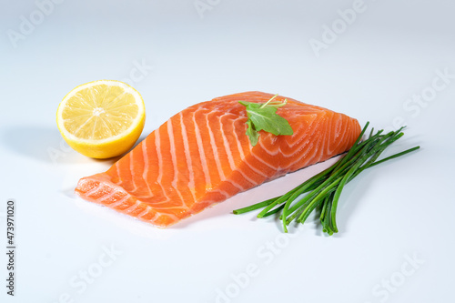 Fresh raw salmon fish fillet, herbs and lemon on isolated background
