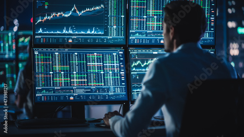 Financial Analysts and Day Traders Working on a Computers with Multi-Monitor Workstations with Real-Time Stocks, Commodities and Exchange Market Charts. Team of Brokers at Work in Agency.