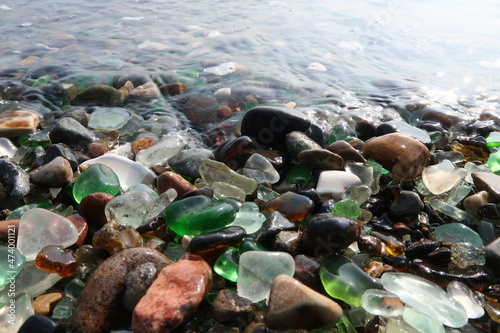 colourful shards of glass polished by sea on a smooth stone, small glass pieces 