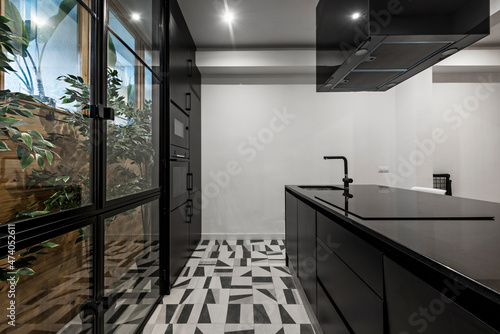 island and kitchen cabinet with black appliances next to a window with plants in a vacation rental apartment