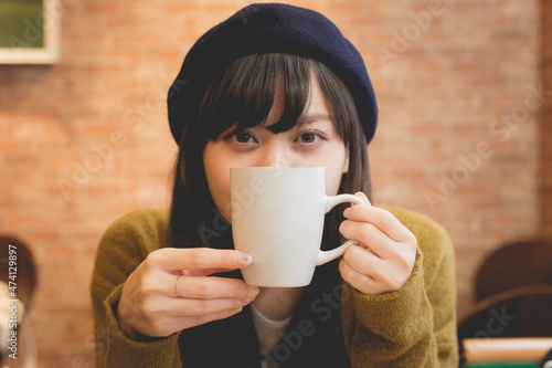 カフェでコーヒーを飲むニットの上着を着た日本人女性 