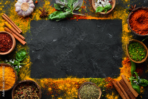 Colorful herbs and spices for cooking. Indian spices. On a black stone background. Top view.