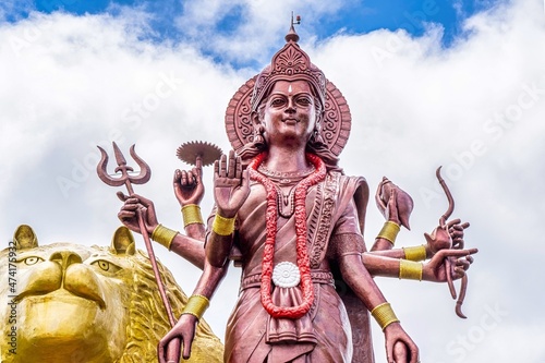 A powerful Statue of the Hindu goddess Durga Maa with a golden lion in sacred Ganga Talao. Grand bassin crater lake, Mauritius island. High quality photo. High quality photo