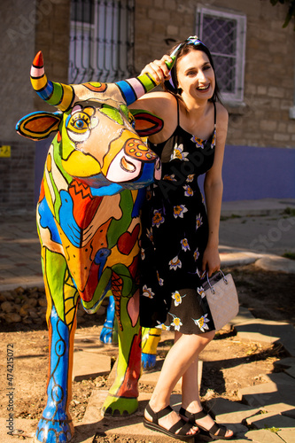 Portrait of a girl with a bull statue on a summer day.