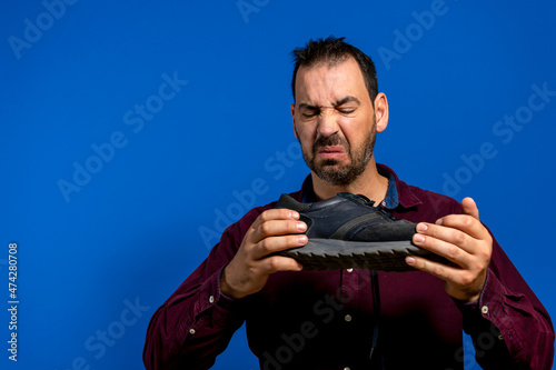 A man hold sneaker in his hands. Nasty smell. Stink legs, fungus on the legs.