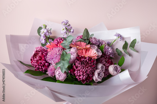 Beautiful bouquet with chrysanthemums, roses, gerbera daisies on pink background. Color of the year 2022. Veri peri
