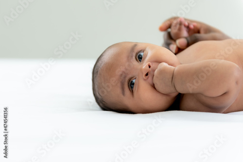 Portrait images of African girl baby newborn is 3-mount-old, lying and smile with happy on white bed, to African child and baby newborn concept.