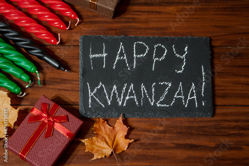 Kwanzaa African American holiday. Seven candles red, black and green on natural wooden background.