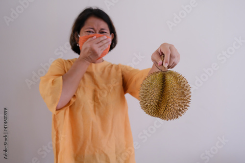 woman covering her nose from smelly Durian fruit in her hand