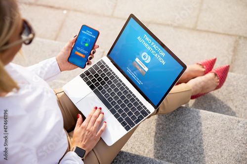 Woman using two factor authentication on laptop and mobile phone