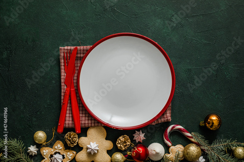 Christmas and New year setting table. White empty plate with cutlery and Christmas tree branches, red napkin on a red concrete background.Christmas menu. New Year eve 2022, Christmas food menu, holida