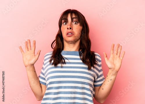 Young Argentinian woman isolated on pink background being shocked due to an imminent danger