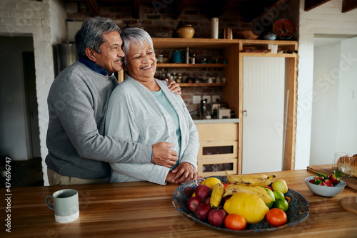 Happily retired elderly biracial couple standing, hugging. Healthy lifestyle in modern kitchen.