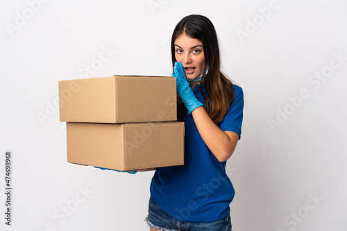 Young delivery woman protecting from the coronavirus with a mask isolated on white background whispering something