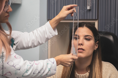 a girl is subjected to a prism bar for the optometrists to analyze the fusional vergences.