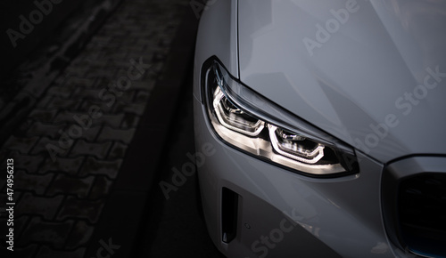 Detail close up view of the LED adaptive head light of premium luxury sedan car. Automotive headlight lighting technology detail.