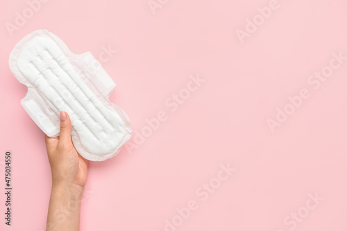 Female hand with menstrual pad on pink background