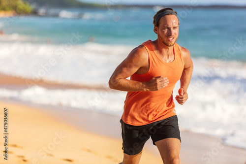 Running athlete man on beach sweating training cardio on intense hiit workout in summer temperature. Male runner active sport lifestyle.