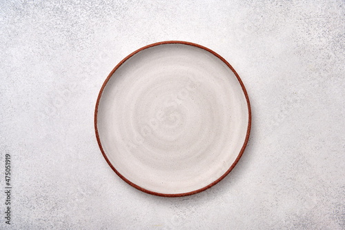 Empty white ceramic plate with brown rim on a light textured background, top view, copy space