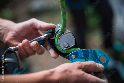 Man's hands operating a rock climbing belaying device