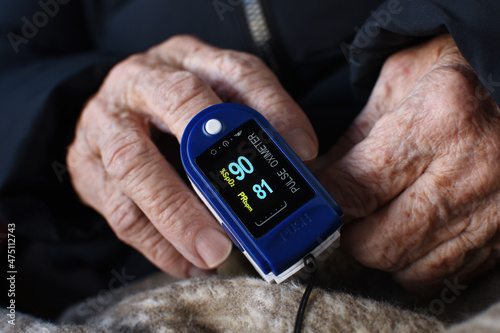 Digital finger oximeter on hand of an elderly woman. Monitoring of pulse and blood oxygen levels at home
