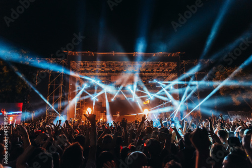 Silhouettes of concert crowd in front of bright stage lights on a music festival