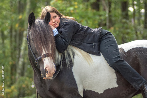Teenage girl lying bareback on Gypsy Vanner Horse mare.