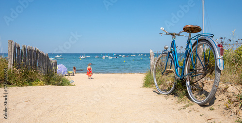 Vieux vélo bleu sur une plage de Bretagne en été.