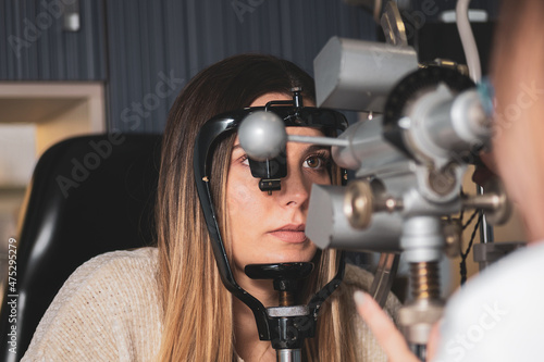 an optician measures a girl's corneal radii with a keratometer in a clinic.