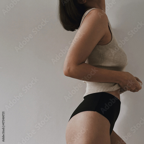 Pretty sexy young woman in neutral beige tee and black panties on white background. Aesthetic elegant fashion vogue composition