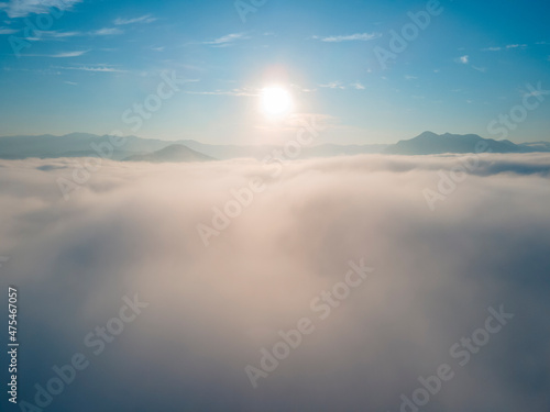 Sunrise over the amazing Sea of fog in the morning with blue sky. Aerial view with a drone among a sea of fog.