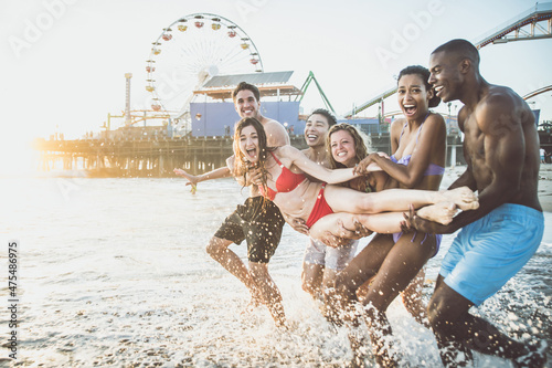 Storytelling image of a group of friends spending time in Santa Monica playing and having fun. Multiethnic young people from california reunited on the beach during a summer day.