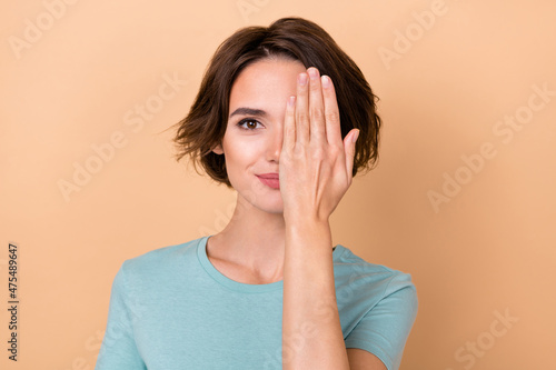 Photo of young pretty woman cover eye hand look clinic check vision isolated over beige color background