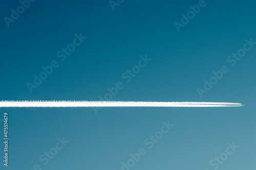 Expressive underlining. A white trail in the sky from a flying plane in freezing weather. Blue sky. Copy space.
