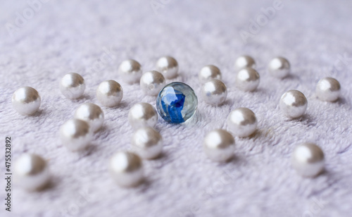 many white pearl and big crystal glass ball on white fur surface. leadership concept background.