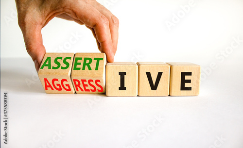 Aggressive or assertive symbol. Businessman turns wooden cubes, changes the word Aggressive to Assertive. Beautiful white background, copy space. Business, psychological aggressive assertive concept.
