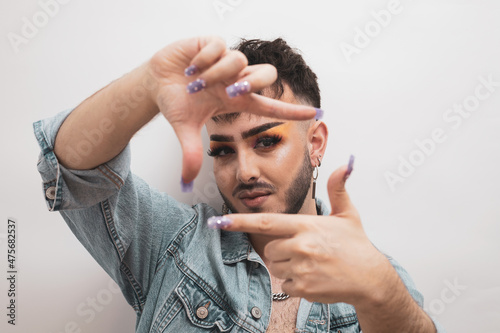 a portrait of a child with makeup making a frame with his fingers on a white background.diversity concept.