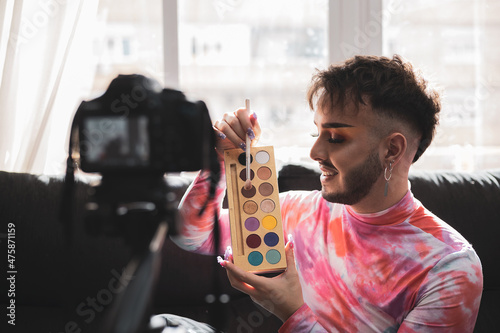 A gay man showing makeup in live video streaming on social media with a video camera. lifestyle and fashion concept.