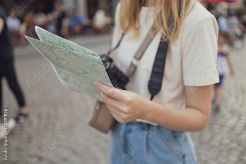 Happy young woman with a city map travelling on a city street, traveling in Europe, freedom and active lifestyle