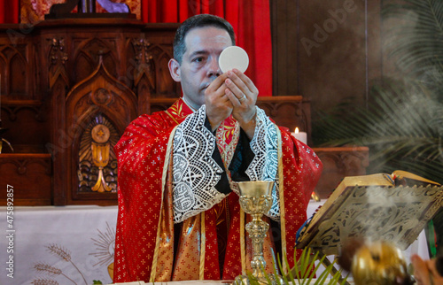 A priest celebrates a catholic mass dressed in a red chasuble 