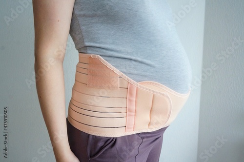 Pregnant woman with orthopedic support belt, bandage for pregnant women at 8 months.