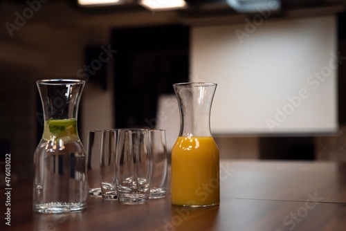 Sala konferencyjna z napojami i szklankami postawionymi na stół dla uczestników.