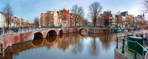 Panorama of Amsterdam canal Keizersgracht with typical dutch houses and bridge during morning blue hour, Holland, Netherlands