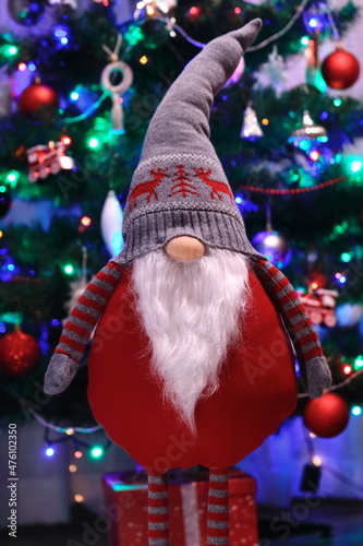 Świąteczny skrzat, krasnal na tle choinki. A Christmas gnome, a leprechaun with a Christmas tree background.
