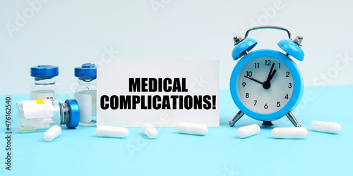 An alarm clock, pills, injections and a card with the inscription - Medical Complications